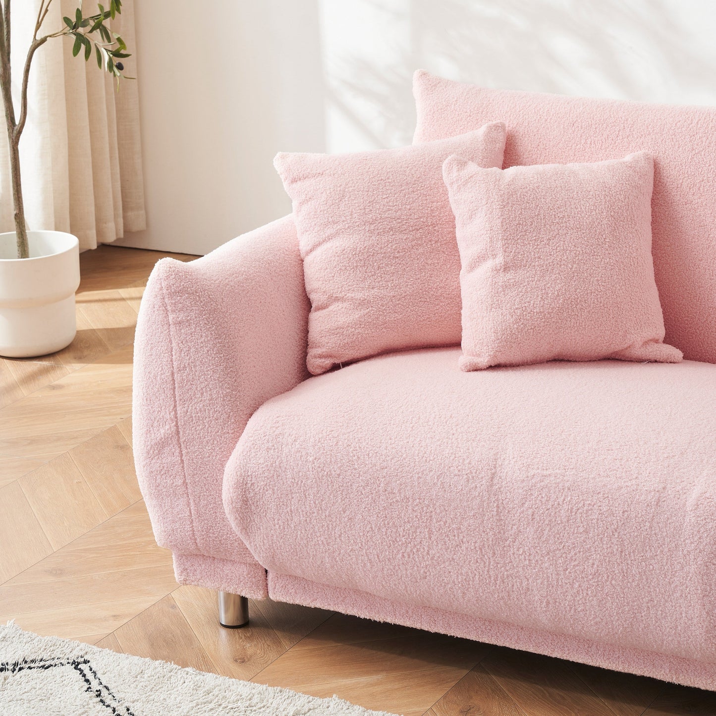 Un canapé rose en polaire de 86,6 pouces avec quatre coussins et des pieds en quincaillerie peut s'asseoir confortablement dans une chambre d'appartement
