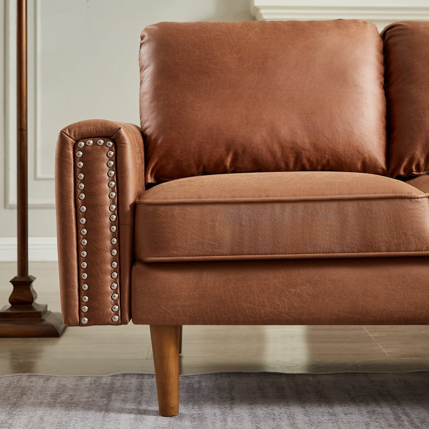 Canapé 3 places en L en cuir synthétique marron de 208 cm avec méridienne gauche et clous décoratifs, finitions cuivrées et pieds en bois massif.