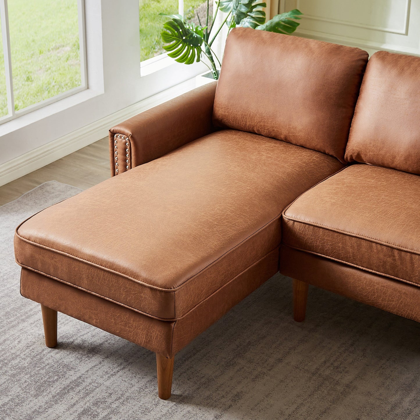 Canapé 3 places en L en cuir synthétique marron de 208 cm avec méridienne gauche et clous décoratifs, finitions cuivrées et pieds en bois massif.