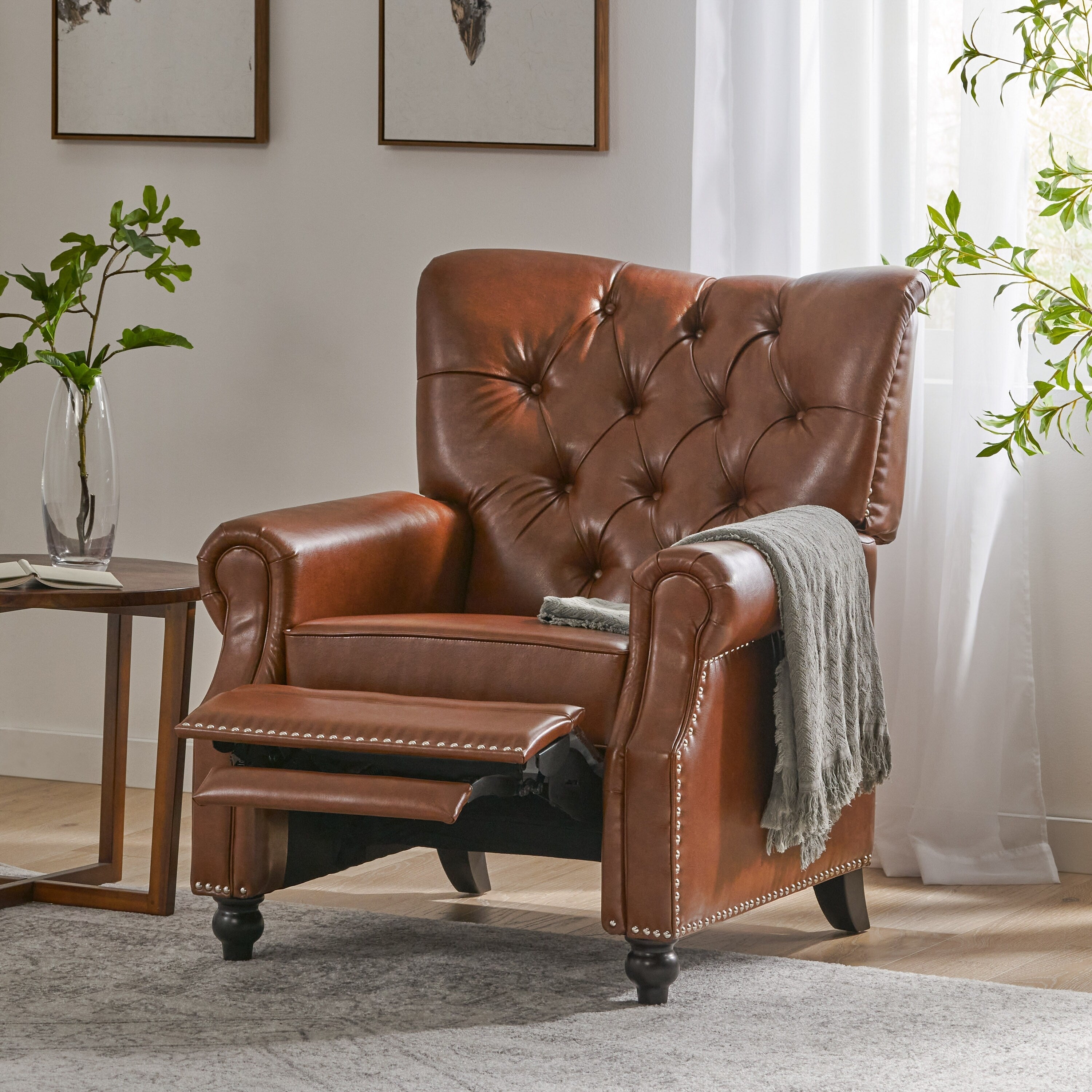 Fauteuil inclinable rembourré en cuir synthétique marron clair avec repose-pieds, dossier capitonné et détails cloutés