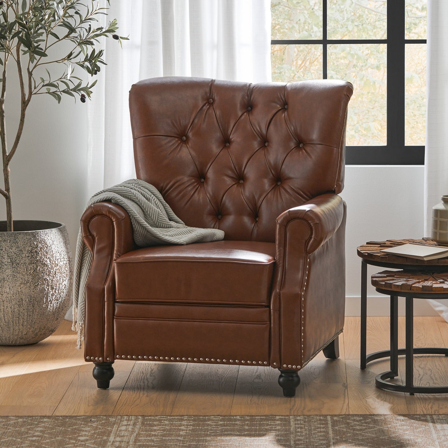 Fauteuil inclinable rembourré en cuir synthétique marron clair avec repose-pieds, dossier capitonné et détails cloutés
