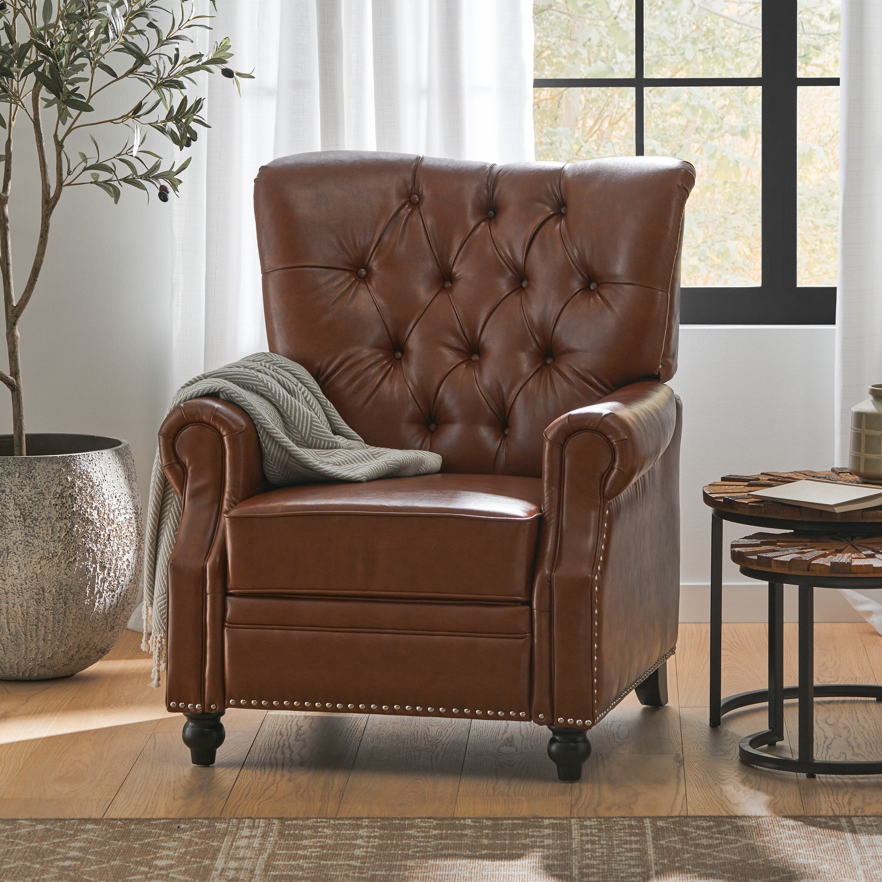Fauteuil inclinable rembourré en cuir synthétique marron clair avec repose-pieds, dossier capitonné et détails cloutés