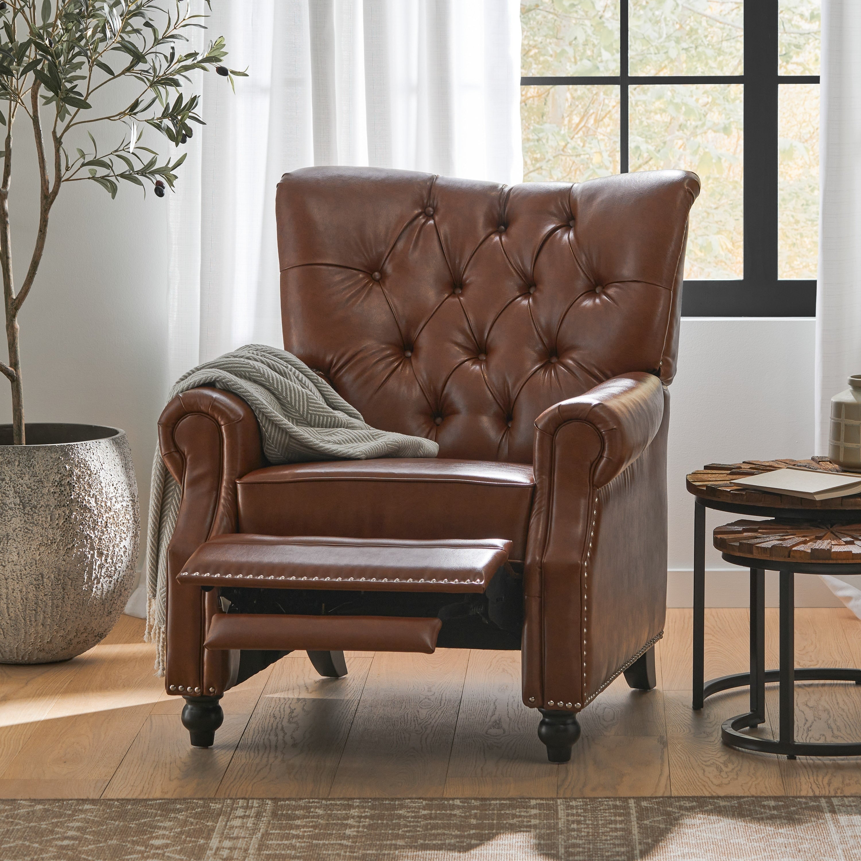 Fauteuil inclinable rembourré en cuir synthétique marron clair avec repose-pieds, dossier capitonné et détails cloutés